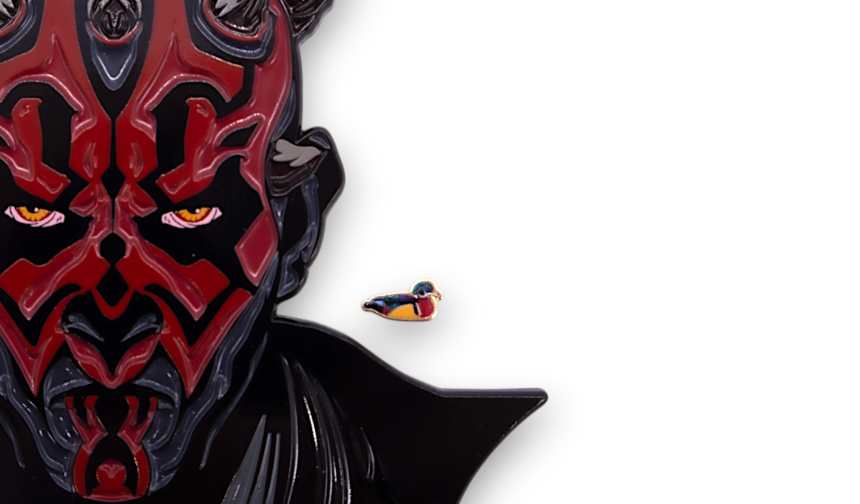 Close-up showing a large Darth Maul enamel pin beside a tiny duck pin badge to demonstrate extreme differences in pin sizes.