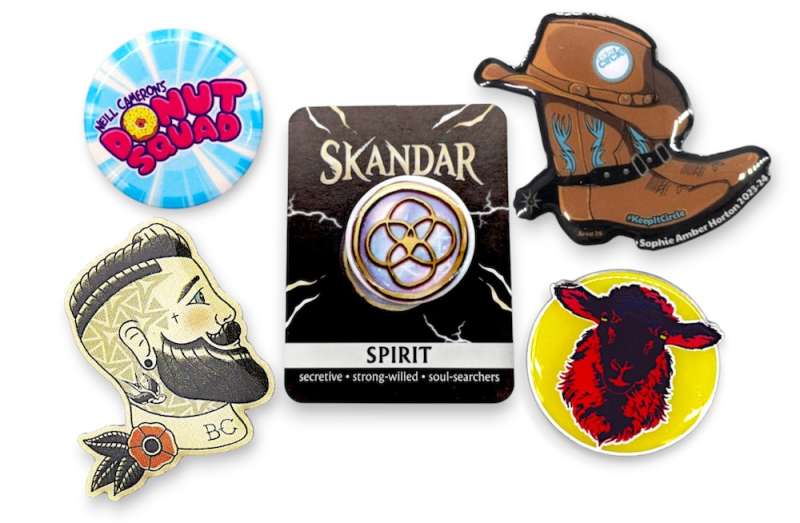 Printed badges with detailed artwork and text showing when complex AI designs can be used without enamel limitations.