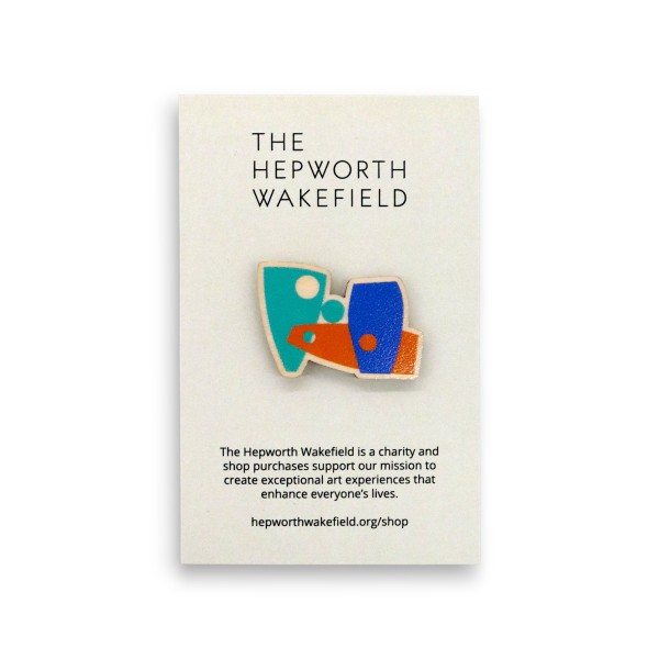 Custom wooden pin badge with abstract geometric design in teal, blue and orange, mounted on The Hepworth Wakefield backing card promoting charity art programme and shop support.